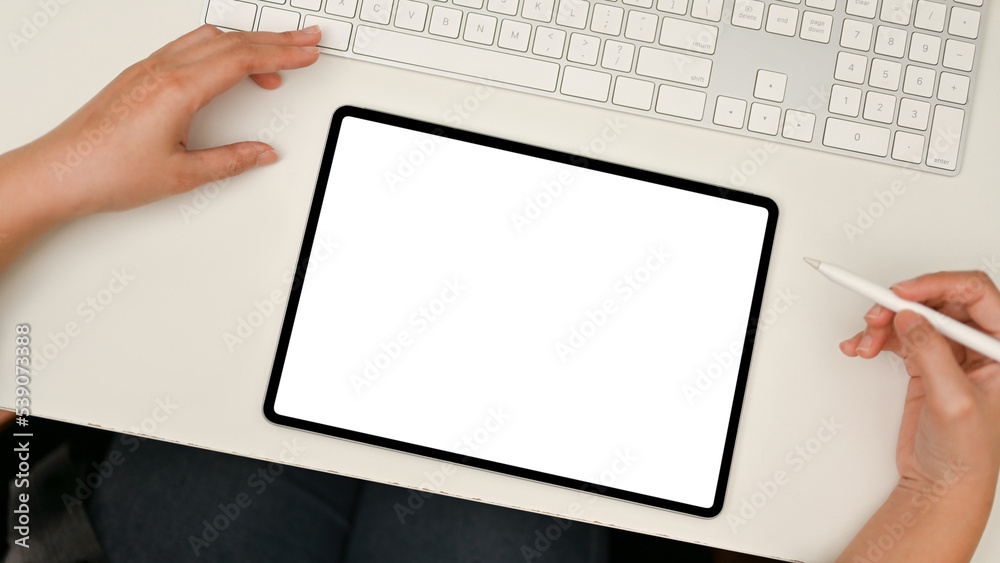 Top view, Tablet mockup on modern white office desk. A female using tablet at her desk. Top view, Tablet mockup on modern white office desk. A female using tablet at her desk.