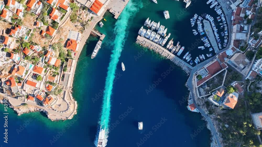 Hydra island in Greece, aerial view of boat leaving harbour of Hydra and marina with yachts in the Mediterranean Sea, Greek Saronic islands vacation, tourism in Greece