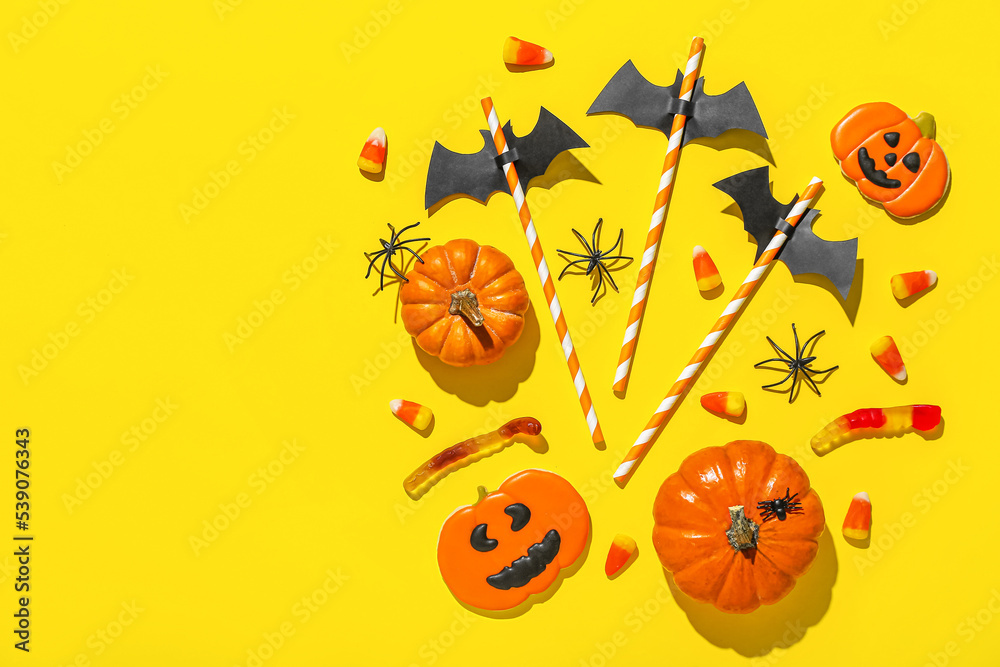Paper bats with straws and Halloween treats on yellow background Paper bats with straws and Halloween treats on yellow background