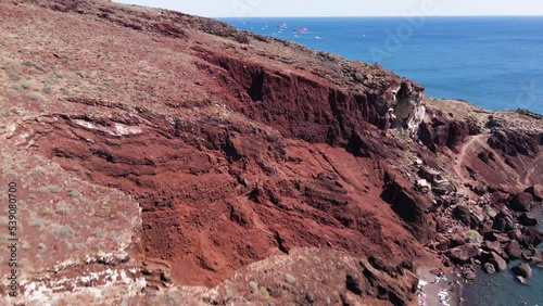 Aerial flying across the cliff edge of Red Beach in Santorini, Greece photo