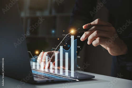 Businessman using computer with graph growth analysis on virtual screen, Growing revenue and Financial business investment concept. photo