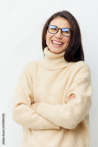portrait of a beautiful cute woman in a beige sweater on a light background in glasses for vision with arms crossed on her chest