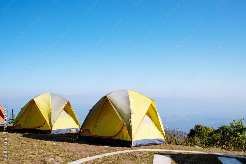 Tent Camping trip outdoor hiking mountain hill. Tent camp in nature background with sunrise on top of mountain. Picnic tent green nature campground in forest. Adventure Travel wildness flare sunlight