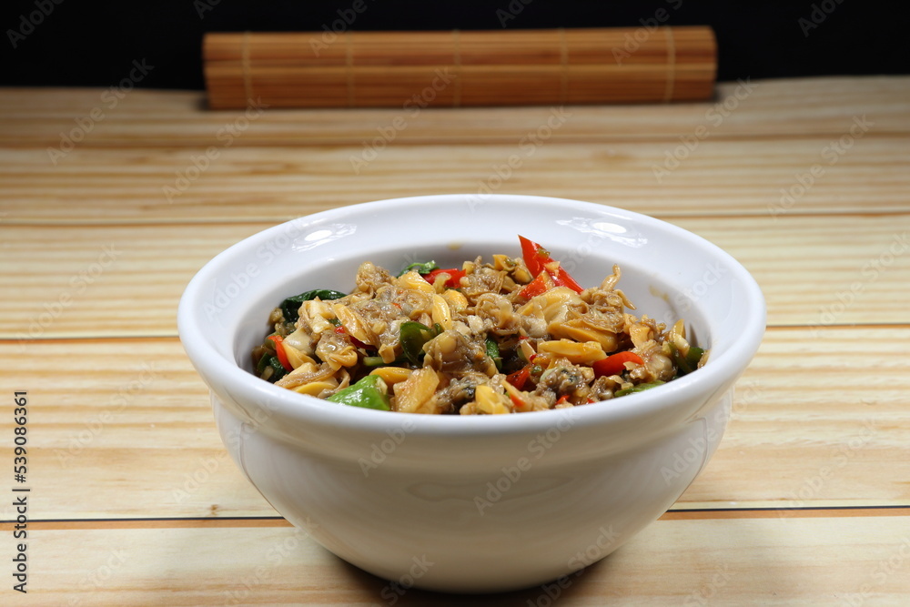 Traditional fried spicy clam meat mixed with basil and chilly serving in the bowl. Traditional fried spicy clam meat mixed with basil and chilly serving in the bowl.
