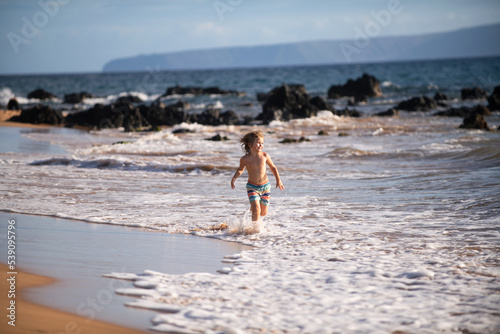 Active little boy splashing in the sea waves on a summer day during the holidays. The concept of family holidays with children.