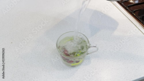 brewing herbal tea with berries and lemon in a transparent cup