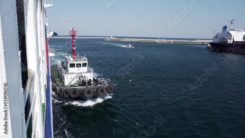 Spring, 2018 - Donghae, South Korea - A tugboat helps dock the East Dream passenger ferry to the quay wall of Donghae city. A small industrial tug in a commercial port.