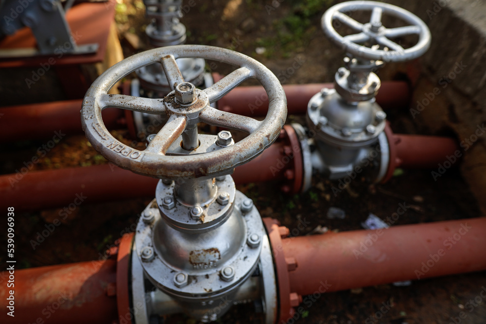 Shallow depth of field (selective focus) details with industrial metallic pipe valves used to open or close the hot water debit inside a big pipeline. Shallow depth of field (selective focus) details with industrial metallic pipe valves used to open or close the hot water debit inside a big pipeline.