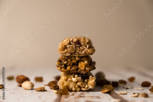 Various energy bars with granola chocolate in a row with scattered nuts, cereals and dried fruits, a grunge background of a white wood table. A healthy vegan snack for fitness. Close-up.