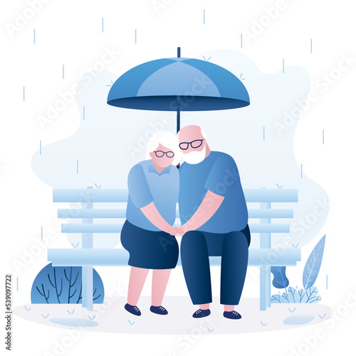 Elderly love couple sits on bench and hugs. Family or lovers with umbrella in the rain. Aged couple in love, expression of emotion, relationship. Grandparents in trendy blue style.
