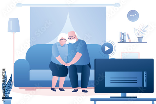 Elderly love couple watching tv. Grandparents sit hugging on the couch. Living room interior. Weekend or evening entertainment. Time together.