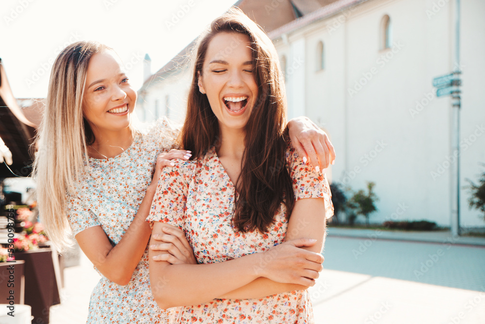 Portrait of two young beautiful smiling hipster female in trendy summer white sundress. carefree women posing on street background. Positive models having fun, hugging and going crazy Portrait of two young beautiful smiling hipster female in trendy summer white sundress. carefree women posing on street background. Positive models having fun, hugging and going crazy