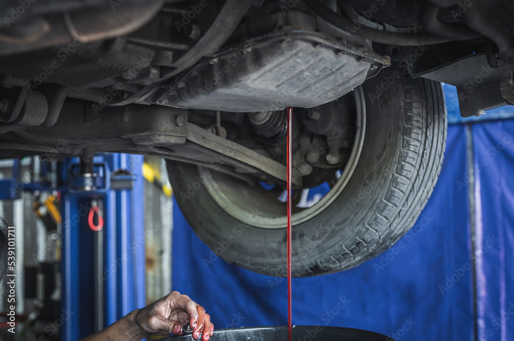 Auto mechanic draining an old transmission fluid out of the