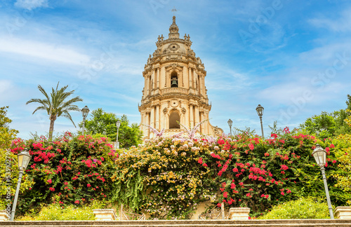 The beautiful staircase with many plants and colorful flowers leads to the Cathedral of S. Giorgio di Modica