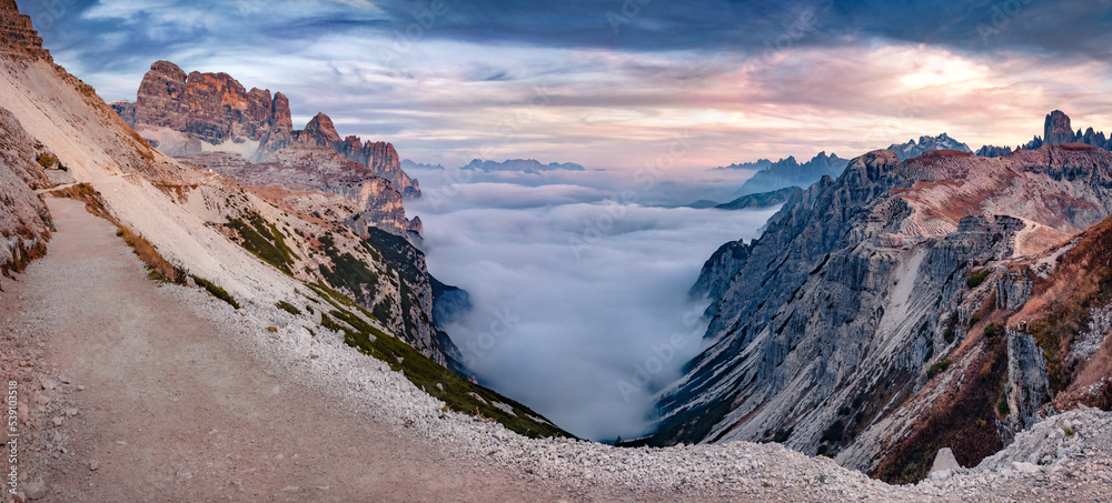 Rocky slopes in Tre Cime Di Lavaredo National Park. Thick fog spreads of mountain canyon. Fantastic autumn view of Dolomite Alps, Italy, Europe. Beauty of nature concept background.