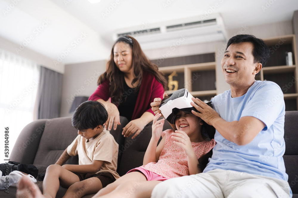 Fototapeta premium children family with mother and father home, happy and smile with virtual reality goggles technology together, person leisure lifestyle to having fun with digital video game by wearing headset
