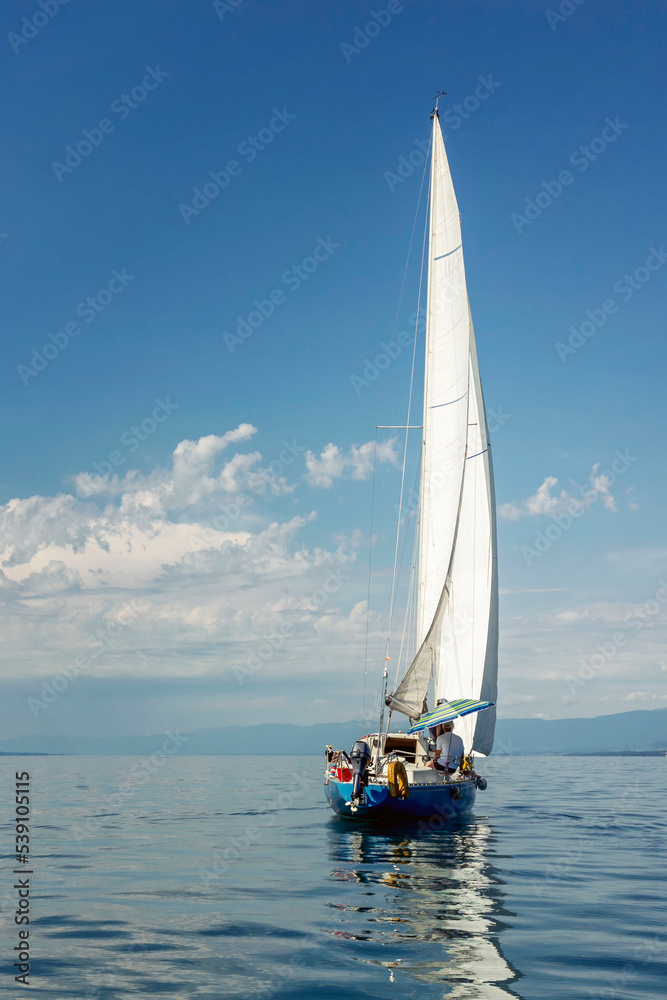 Naklejka premium Sailing yacht on a sunny calm day at sea. Activity, sports and recreation. Beautiful landscape. Vertical.