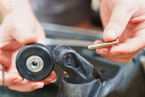 replacing the old erased wheel on the suitcase with a new one. the concept of reasonable consumption and repair of old things. repairman's job.