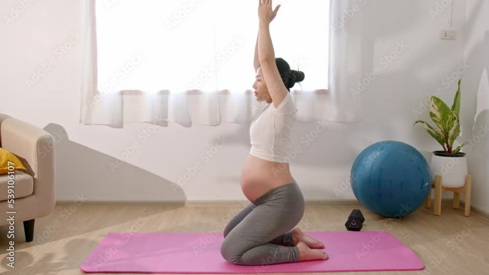 Asian Pregnant woman doing yoga exercise at home.