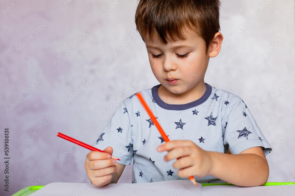 Little boy drawing with color pencils. Boy, drawing a picture for fathers day. Small boy draws at the table. Little boy drawing with color pencils. Boy, drawing a picture for fathers day. Small boy draws at the table.