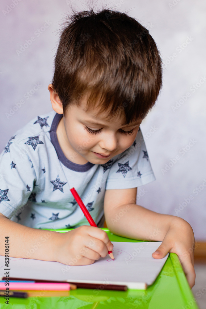 Little boy drawing with color pencils. Boy, drawing a picture for fathers day. Small boy draws at the table. Little boy drawing with color pencils. Boy, drawing a picture for fathers day. Small boy draws at the table.