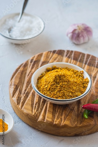 Spicy Svan salt in a white bowl on a wooden board on a light concrete background. Recipes for spices, spicy salt.