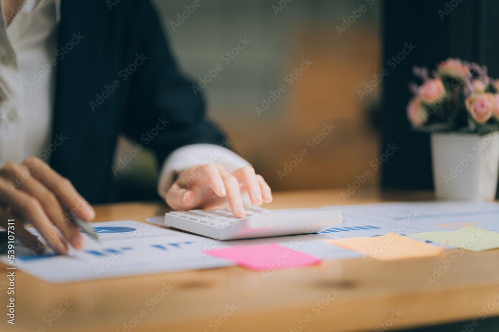 business woman or accountant who are using a calculator to calculate business data Accounting documents and laptop computer at the office business idea