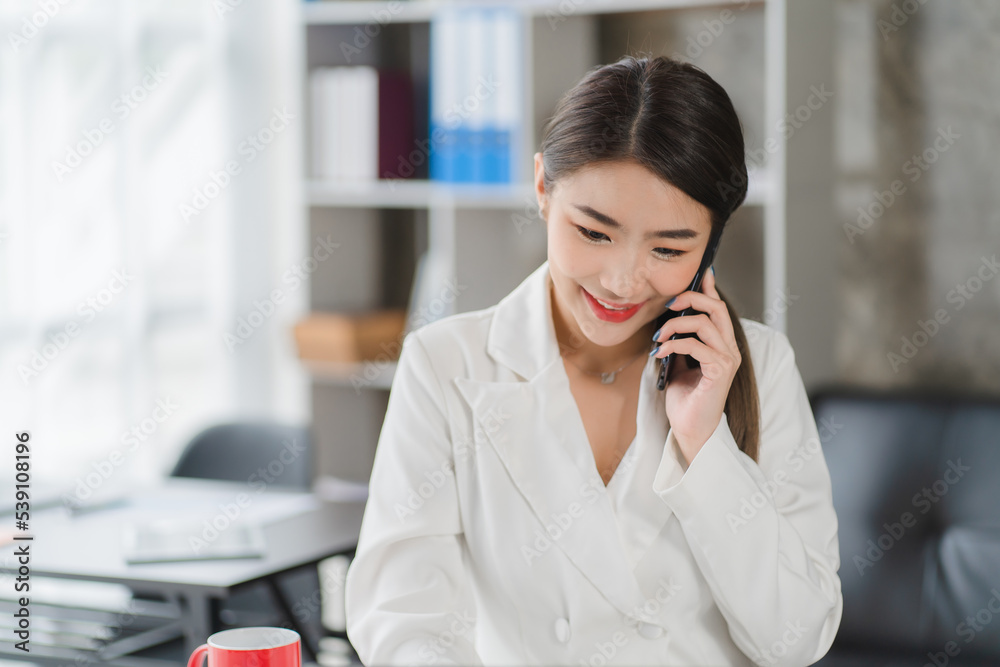 Young asian businesswoman beautiful charming smiling and talking on the mobile phone in the office Young asian businesswoman beautiful charming smiling and talking on the mobile phone in the office