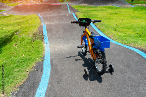 Child bicycle on Off-Road Cycling Course.Asphalted bicycle pump track  racing speed track with traffic lines for  BMX racing track or Bicycle Motocross and Roller skating with sunlight background.
