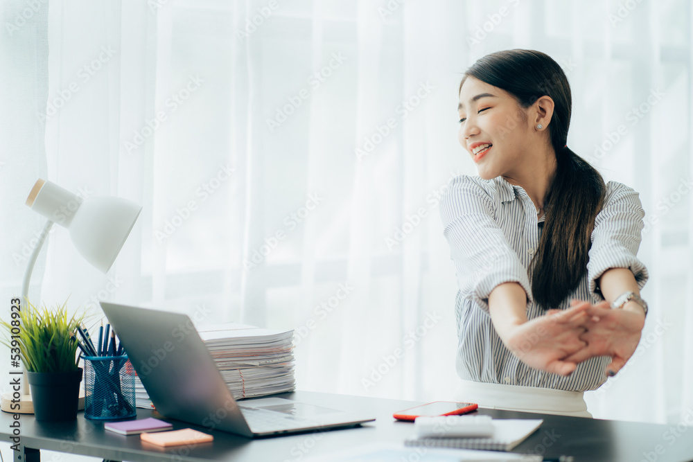 Portrait of smiling happy beautiful Asian woman relaxing using technology of laptop computer while sitting on table.Young creative girl working and typing on keyboard at cafe.work at home concept Portrait of smiling happy beautiful Asian woman relaxing using technology of laptop computer while sitting on table.Young creative girl working and typing on keyboard at cafe.work at home concept