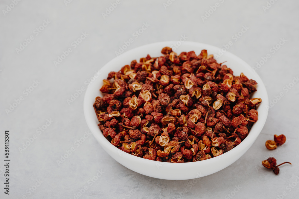 Sichuan pepper. Chinese pepper (Zanthoxylum schinifolium) in bowl on gray stone background. Sichuan pepper. Chinese pepper (Zanthoxylum schinifolium) in bowl on gray stone background.