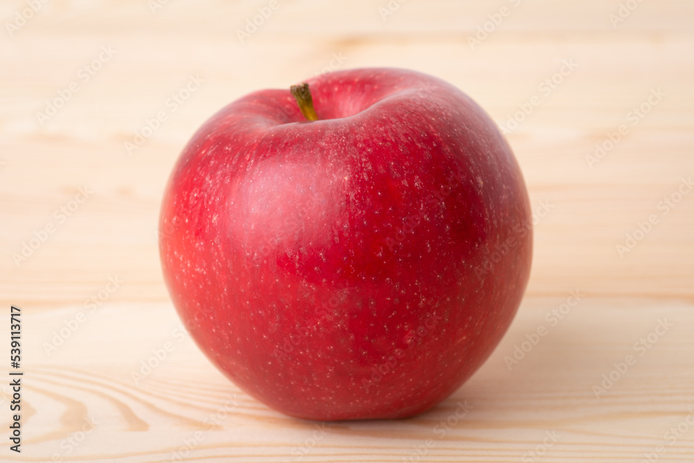 Red fresh apple on wooden background. Close up shot of an apple on the table Red fresh apple on wooden background. Close up shot of an apple on the table