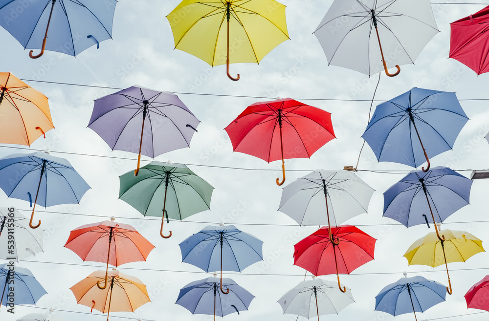 Many colorful umbrellas background. Opened umbrellas in the sky. Urban decoration. Bottom view.