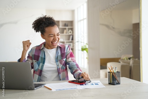Excited mixed race teen girl student got good news email on laptop celebrates personal achievement