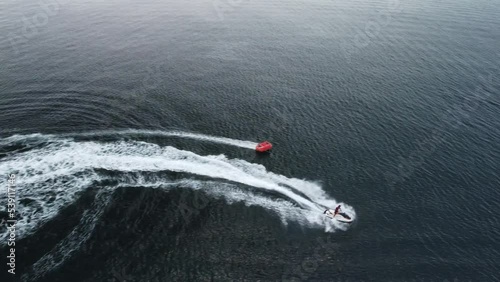 Wallpaper Mural Happy people are going to swim on an air mattress behind a jet ski. Tourists ride the inflatable watercraft boat. Sea attraction. Jet ski skating people on a large Inflatable raft. Aerial copter view. Torontodigital.ca