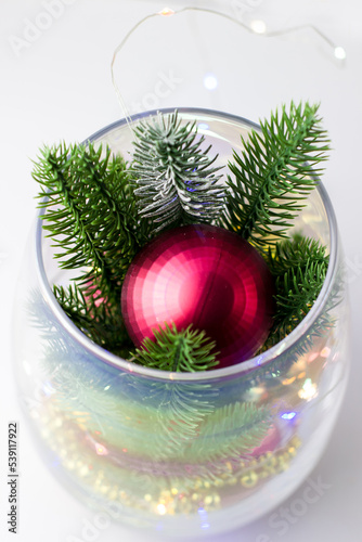 Christmas decoration made of spruce branches and red balls. Christmas decor in a transparent vase on a white background