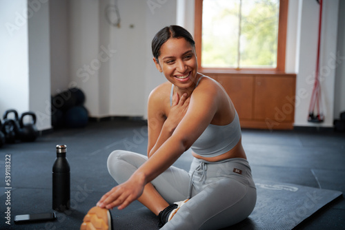 Confident young biracial woman doing stretching exercise at the gym