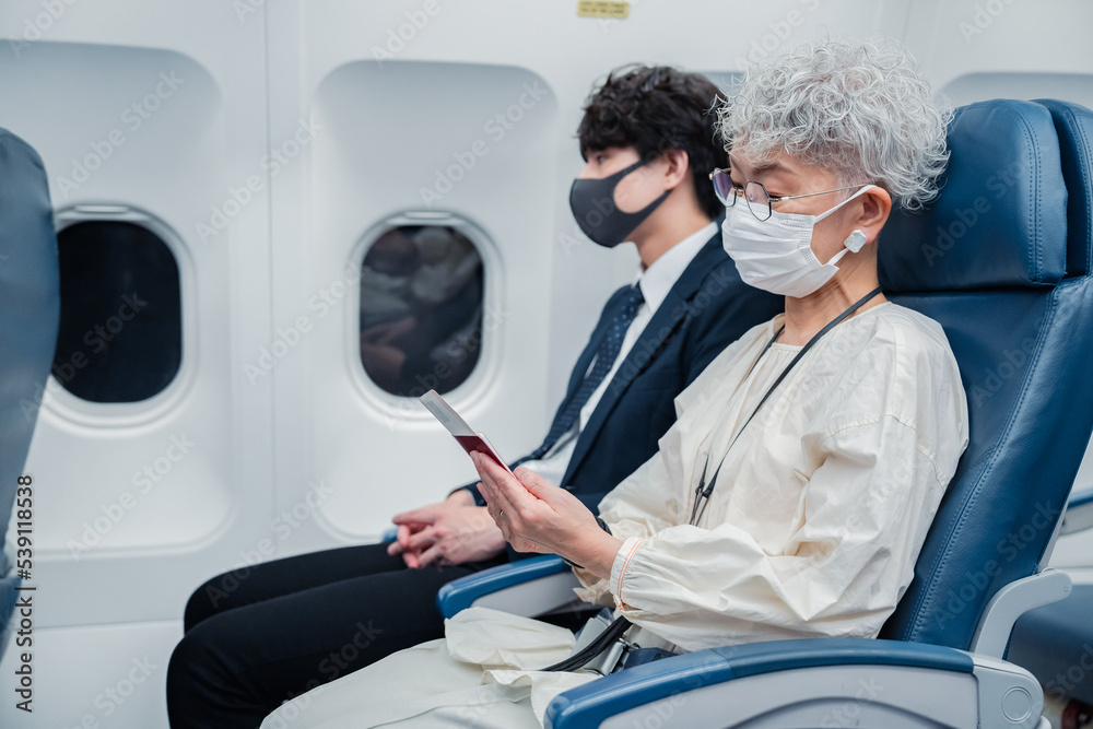 飛行機で旅行をする高齢の女性 飛行機で旅行をする高齢の女性