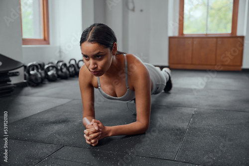 Athletic young biracial woman doing plank exercises at the gym © StratfordProductions