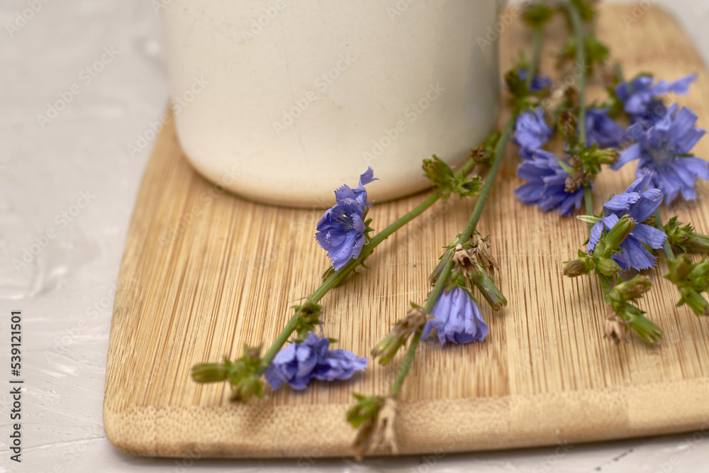 a mug with a drink and chicory flowers on a cutting board