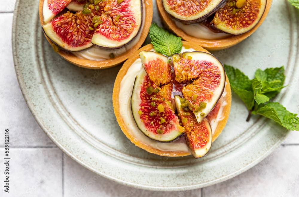 Delicious tartlet with crispy almond-flavored pastry, delicate cheese cream and figs, gray tilled background. Autumn dessert. National Dessert Day, October 14. Delicious tartlet with crispy almond-flavored pastry, delicate cheese cream and figs, gray tilled background. Autumn dessert. National Dessert Day, October 14.