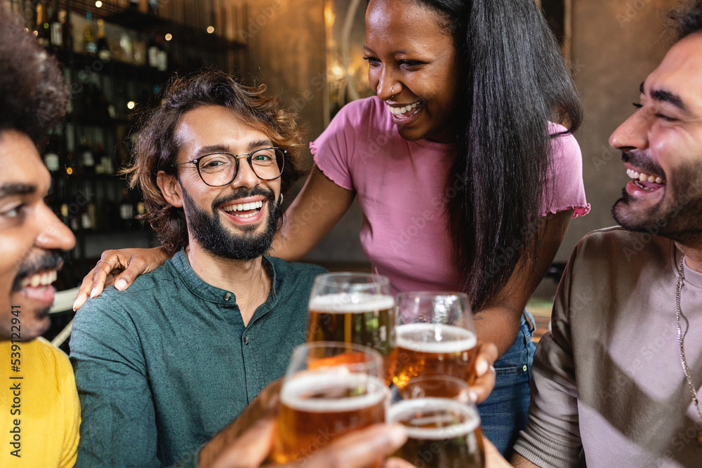 Multiracial group of young best friends talking and having fun drinking at brewery bar - Multiethnic people enjoying happy hours together at irish pub toasting craft beer Multiracial group of young best friends talking and having fun drinking at brewery bar - Multiethnic people enjoying happy hours together at irish pub toasting craft beer