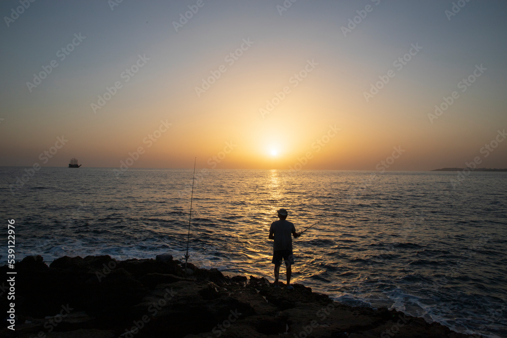 wide angle of sunset and a fisherman fishing alone