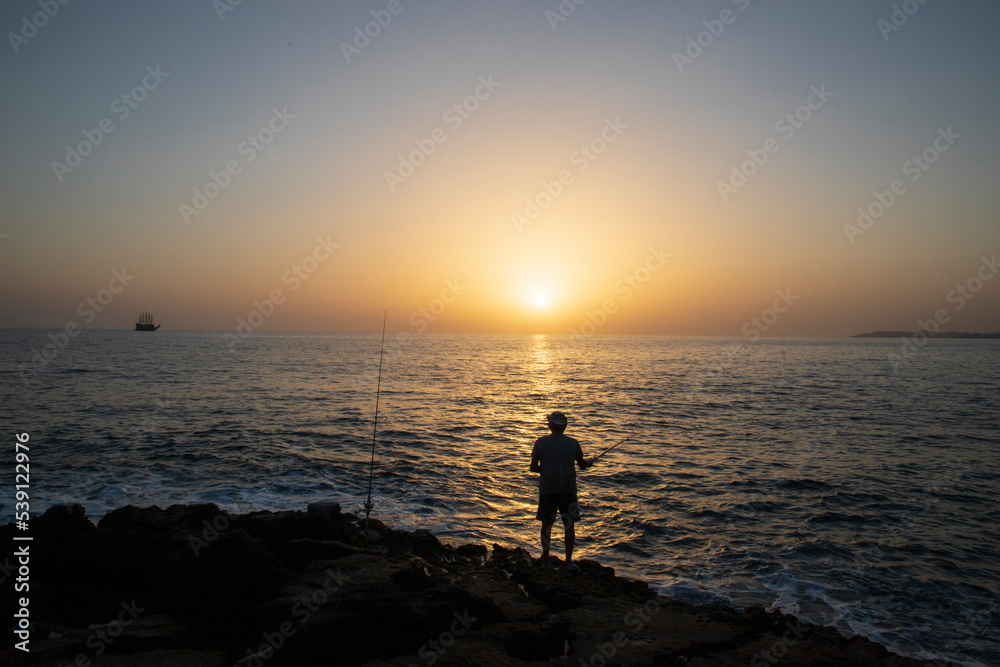 wide angle of sunset and a fisherman fishing alone wide angle of sunset and a fisherman fishing alone