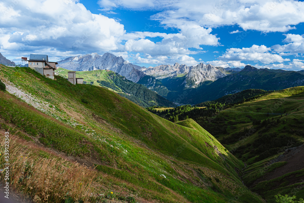 Obraz premium The view of the Dolomites seen from the Sella pass with the lights of the sunset, one of the most famous places in the Alps, near the town of Canazei, Italy - August 2022.