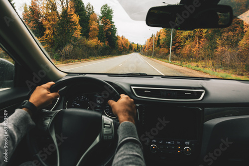 Man driving car on the country road in autumn.