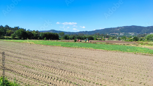 Farmer in tractor preparing land with seedbed cultivator in farmlands. Tractor plows a field. Agricultural work in processing, cultivation of land. Farmers prepare the land and fertilize it.