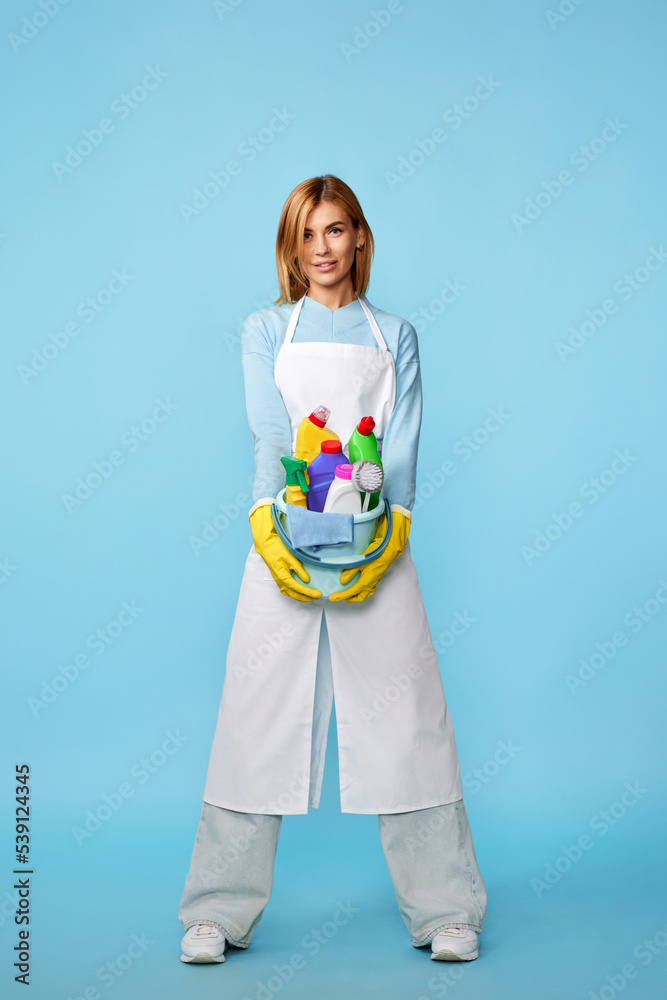 woman in rubber gloves and cleaner apron with cleaning supplies