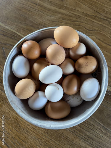 Close up shot from above of an aluminium bowl filled with fresh laid eggs of different shell colors, white and pink. Farm style food.