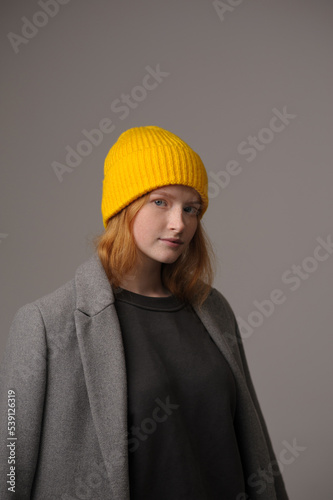 young girl model in yellow hipster hat and coat isolated on light background. Product photo mockup for fashion brands and marketplaces, woolen cap, turkish textiles. © Юрий Горид